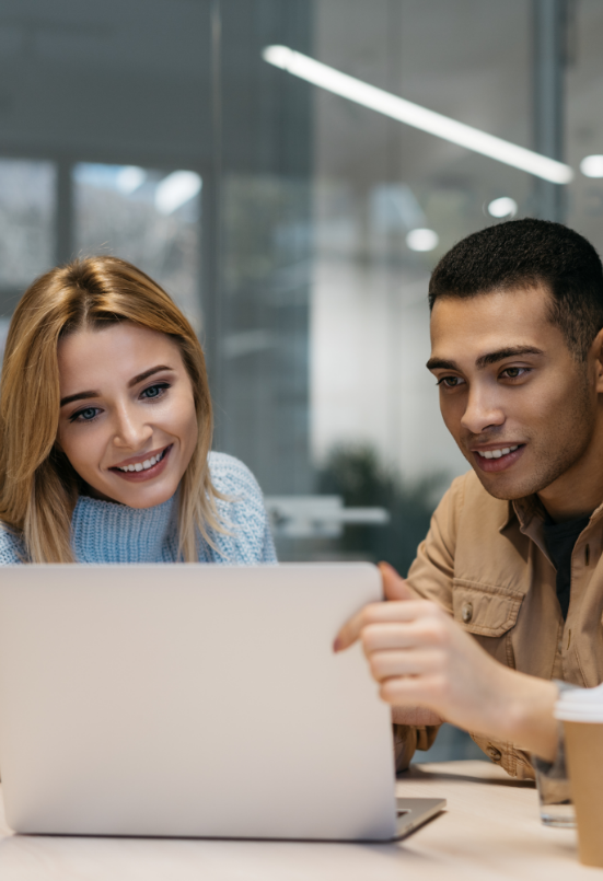 Two ACCA students who are both smiling at a laptop during their studies. 